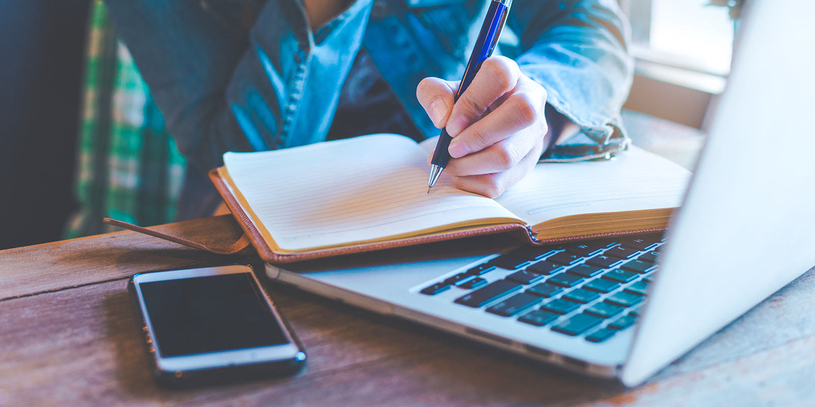 A developer takes notes beside a laptop and smartphone during user testing.