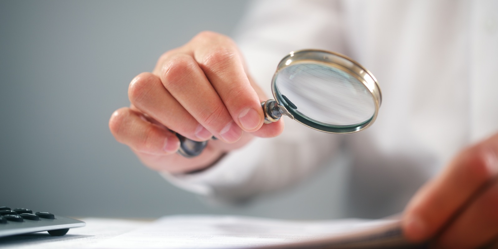 Someone examining a document through a magnifying glass.