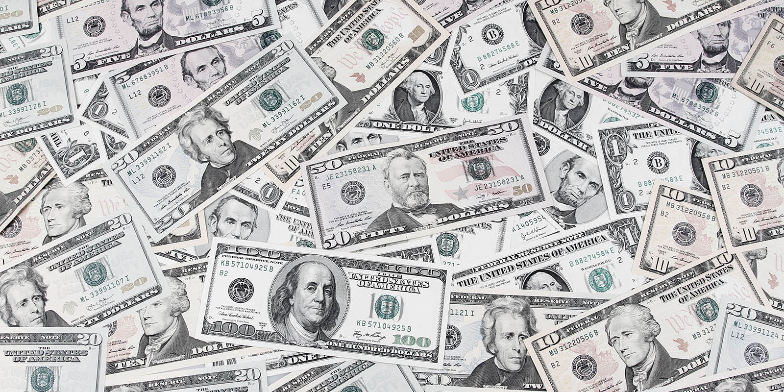 A scattered pile of US dollar bills in a range of denominations.